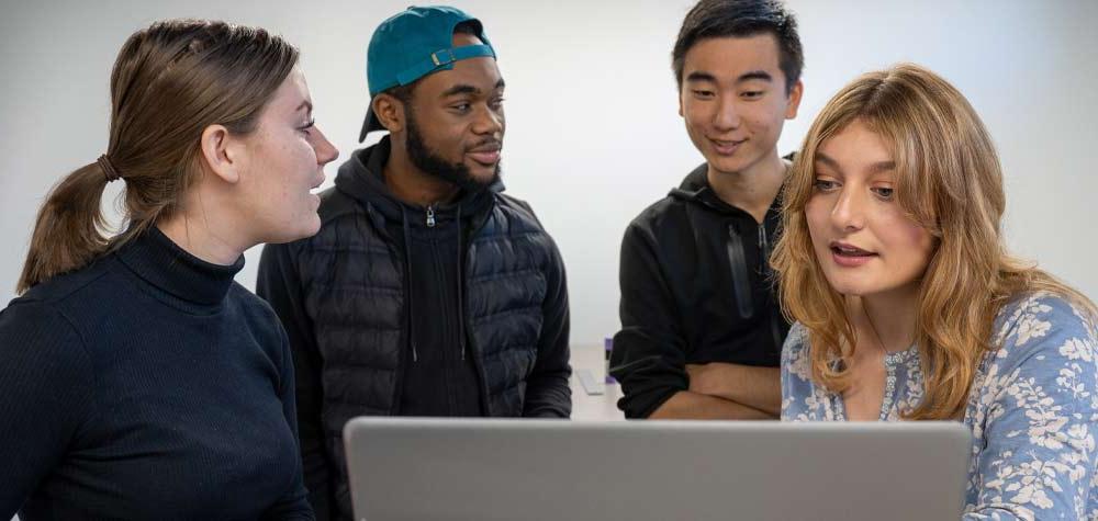 4个学生围着一台笔记本电脑